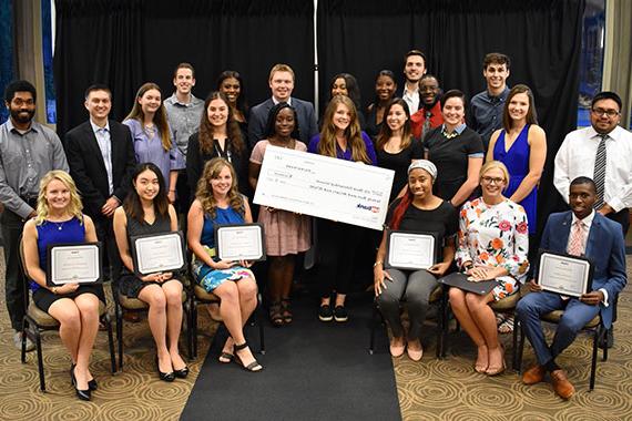 Students holding large paper check representing financial assistance